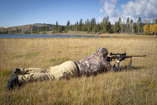 身着迷彩的猎人俯卧着步枪瞄准