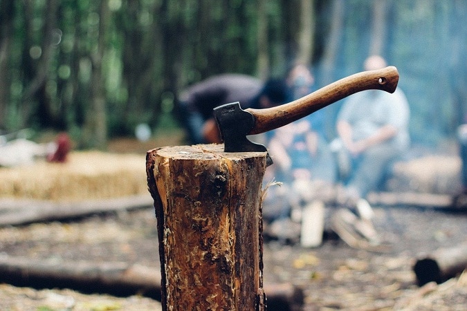 篝火旁劈开的木头上的斧头