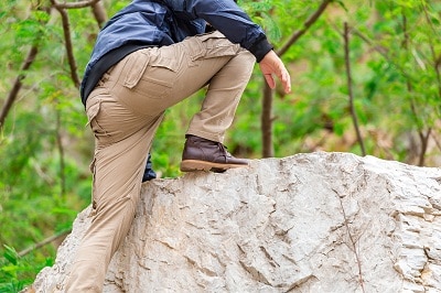 穿着工装裤的男人爬上岩石