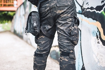 一个穿着迷彩军裤的城市男人站在墙边。
