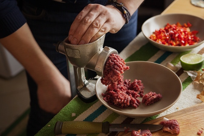 男人的手用绞肉机绞肉