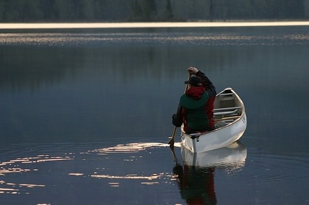在平静的水面上划独木舟的人