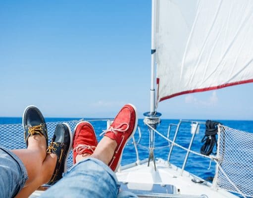 两条腿在红色和蓝色白色游艇甲板上平底便鞋