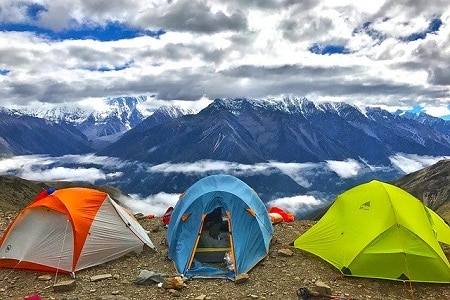 地上有三顶帐篷，俯瞰群山