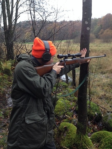 猎人瞄准步枪在树下在秋天