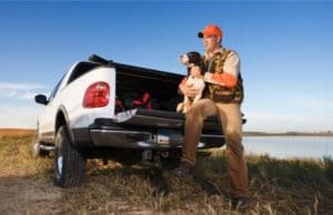 Hunter with dog sitting on truck