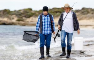 手持渔具的渔民在岸边行走