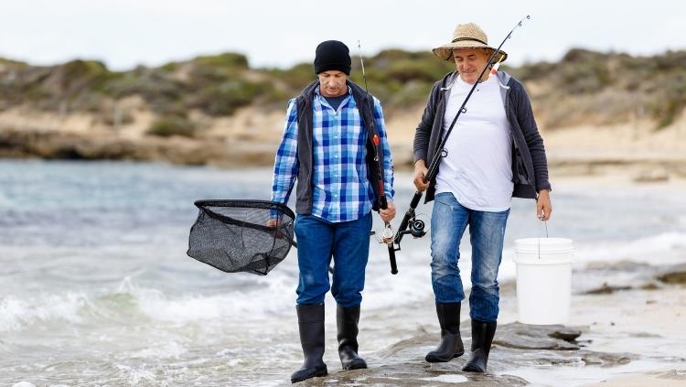 手持渔具的渔民在岸边行走