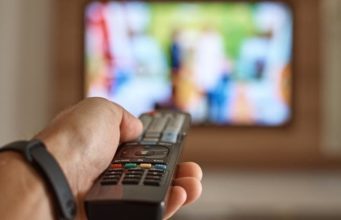 man holding remote in front of TV