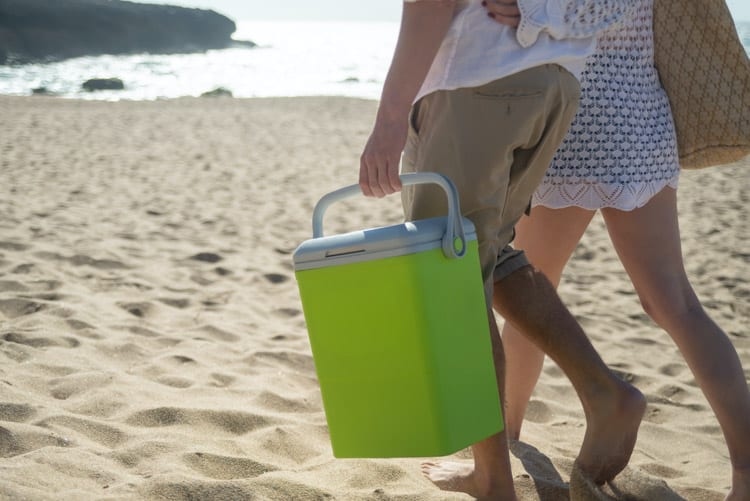 一对夫妇在海滩上携带小型硬边冷却器
