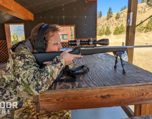 男子在狩猎迷彩测距距离与步枪瞄准镜坐在枪靶场板凳