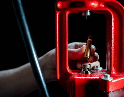 A hand inserting a 6.5 creedmoor rifle casing into a reloading press