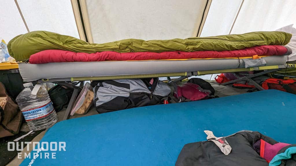在寒冷天气的热帐篷的睡眠系统的侧面，包括一个小床，垫，睡袋，羽绒被与包在小床下