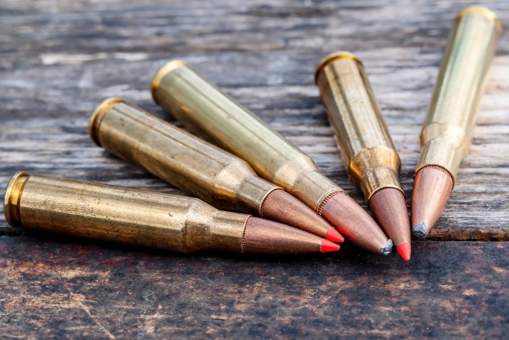 五个猎枪子弹与红色和银色提示关闭坐在一张桌子