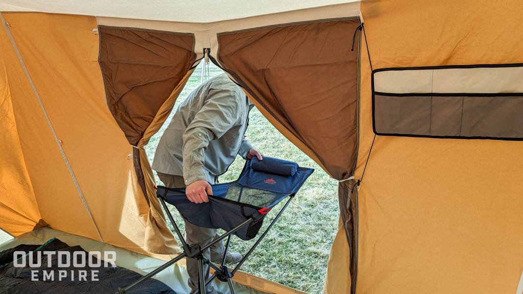 人携带露营椅通过帐篷的门